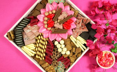 Çikolatalı tatlı şarküteri otlatma tepsisi modern pembe arka planda.