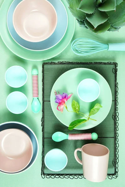 Modern pastel pink, green and blue ceramic tableware set on pale green. — Stock Photo, Image