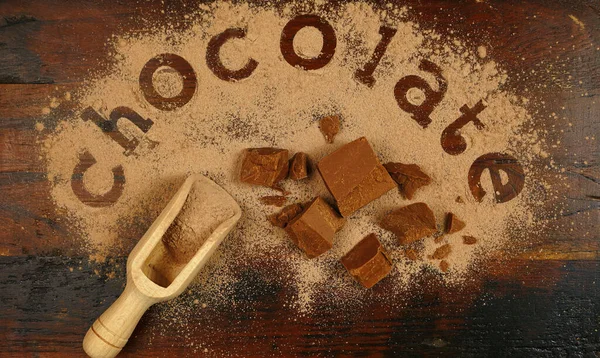 The word chocolate spelled into chocolate powder on dark wood vintage table. — Stock Photo, Image