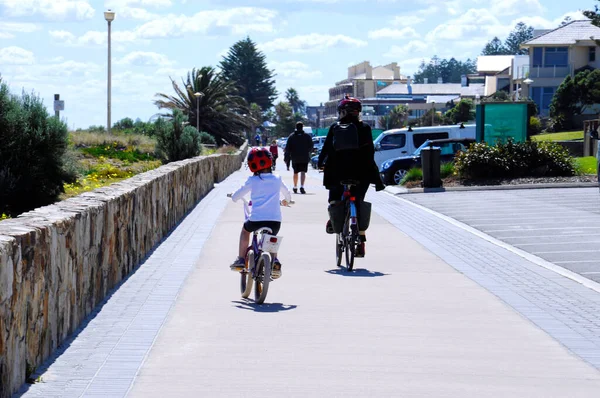 Mother and daughter on bicycles cycling along the Esplanade walkway.