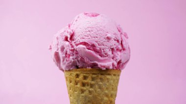 Dondurma aromalı çilek. Pembe arka planda waffle külahında kepçelenmiş. Yakın plan yiyecek konsepti..         