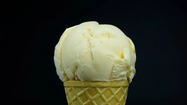 Ice cream flavor Vanilla scoop in waffle cone on black background, Front view Food concept.