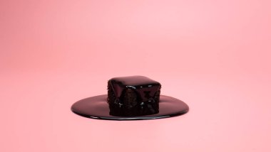 Çikolatanın tepesinde çikolatalar var. Pembe arka planda izole edilmiş. Gıda konsepti.