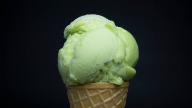 Siyah arka planda waffle külahında kepçe limon aromalı dondurma..