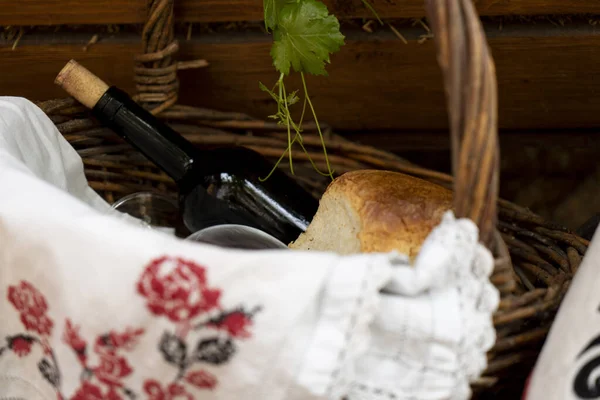 Bir şişe şarap, ahşap bir arka planda üzüm sepetinde ekmek.