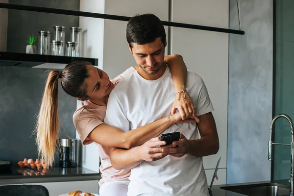 Güzel, mutlu, genç bir çift kahvaltıda akıllı telefon kullanıyor.