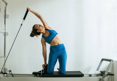 Bir Cadillac veya trapeze masa kullanarak Pilates Egzersiz yapan kadın