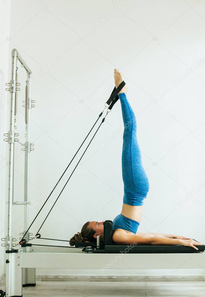 Woman performing Pilates exercise using a Cadillac or Trapeze table