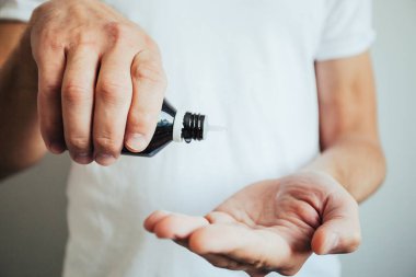Yetişkin bir adamın el dezenfektanı kullanması.