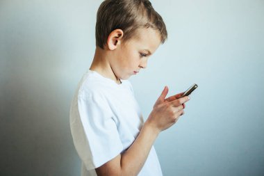 Yalıtılmışken cep telefonu olan şirin bir çocuk.