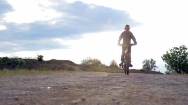 Bir çocuk kır yolunda bisiklete biner. Çocuk bisikleti. Aktif yaz tatili. 