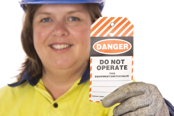 A female worker showing an Out of Service Tag, important for tagging out unsafe machinery.