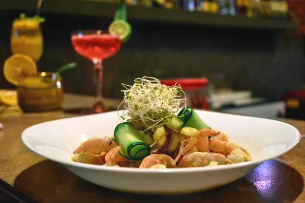 Shrimp dish with green sauce and salad.