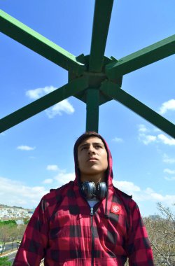 Kırmızı kazak giyen ve gökyüzünü gören siyah kulaklıklı genç adamın portresi..