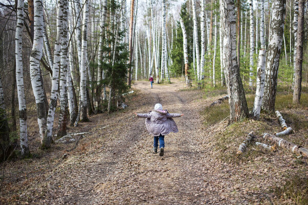 family walk outdoor. happy child runs along forest road with his arms spread out like wings. concept of freedom.
