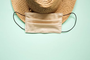 2020 yazının konsepti: Hasır şapka ve temiz arka planda kadın maskesi. Coronovirüs covid tatil seyahati