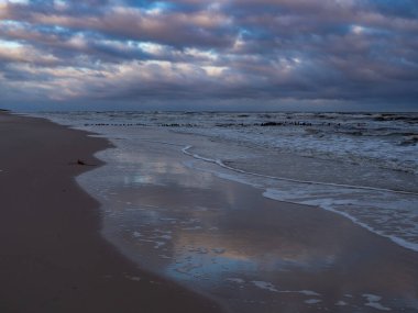 Güneş doğduktan sonra, Polonya 'nın Piasnica Nehri kıyısında, Debki plajında. İskelenin kalıntıları ve muhteşem gökyüzü.