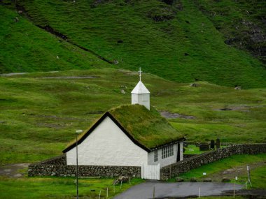 Faroe Adaları, Streymoy, Saksun. Saksun 'un kilisesine ve vadisine bakın. Çimen çatılı beyaz bina yeşil alanların dışında duruyor..