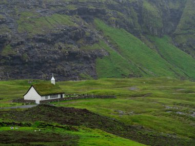 Faroe Adaları, Streymoy, Saksun. Saksun 'un kilisesine ve vadisine bakın. Çimen çatılı beyaz bina yeşil alanların dışında duruyor..