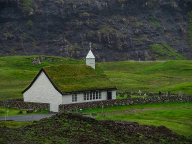 Faroe Adaları, Streymoy, Saksun. Saksun 'un kilisesine ve vadisine bakın. Çimen çatılı beyaz bina yeşil alanların dışında duruyor..