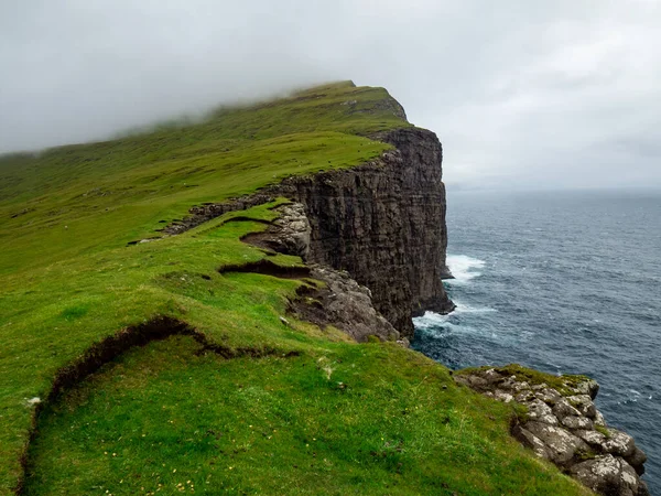 Faroe Adaları 'nın kayalıkları. Okyanus altında. Ön planda yeşil çimen alanları.
