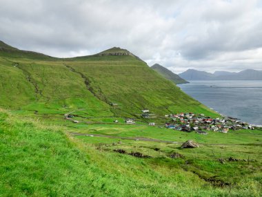 Faroe Adaları, Eysturoy, Eğlence Kommuna. Vadideki kasabanın manzarası. Yeşil tarlalar, yeşil dağlar ve okyanuslarla çevrilidir..