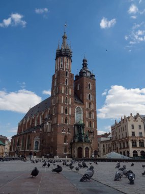 Krakow / Polonya - 22 / 04 / 2020. Coronavirus covid-19 salgını sırasında Krakow 'daki neredeyse boş ana meydan. Turistler tarafından rahatsız edilmeyen Sukiennice ve güvercinlere bakın..