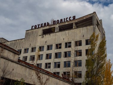 Pripyat 'ın terk edilmiş hayalet kasabasındaki Polissia Oteli. Pripyat, Çernobil sınırlama bölgesindeki aşırı gelişmiş ağaçlar ve yıkılan binalar. Çatıdaki yazıt - Otel Polissya. Ukrayna