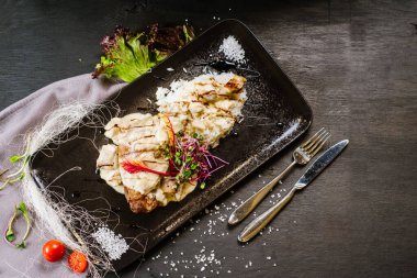 Siyah arka planda sosun altında kızarmış tavuk budu.