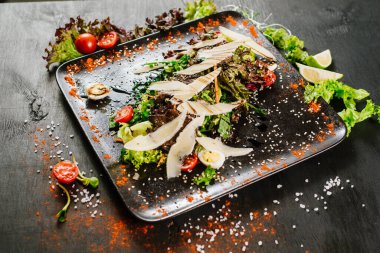 Peynirli et yemeği ve siyah arka planda serseriler.