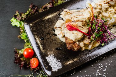 Siyah arka planda sosun altında kızarmış tavuk budu.