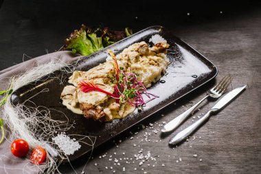 Siyah arka planda sosun altında kızarmış tavuk budu.