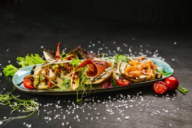 Siyah arka planda karışık et ve sebzeli bir yemek.