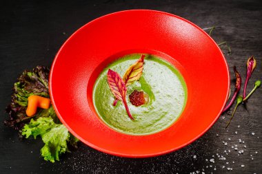 Kırmızı tabakta havyarlı yeşil kremalı çorba.