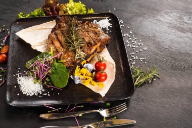 Siyah arka planda ızgara mermer biftek tabağı.