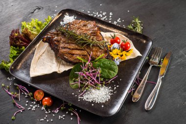 Siyah arka planda ızgara mermer biftek tabağı.