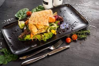 Pide içinde kırmızı balık bifteği ve siyah üzerine sebze.