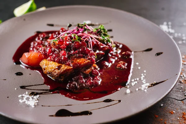 Tasty dish with meat, cranberry sauce and pear on black background