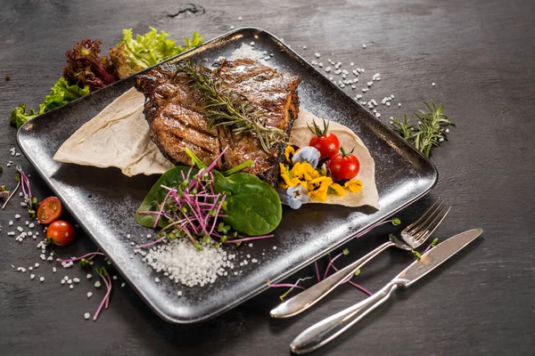 Siyah arka planda ızgara mermer biftek tabağı.