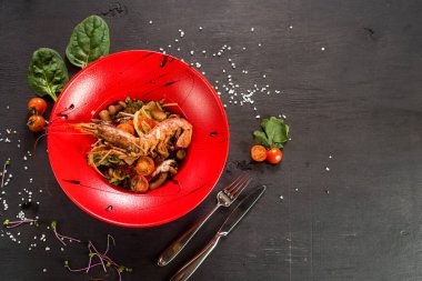 Büyük karidesli bir salata, ahşap arka planda havyar ve sebze.