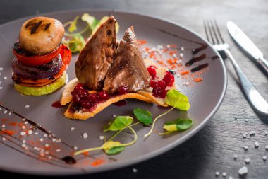 Lezzetli pişmiş et soslu, siyah arka planda sebzeli tabak.