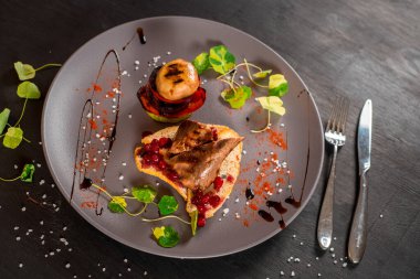 Lezzetli pişmiş et soslu, siyah arka planda sebzeli tabak.