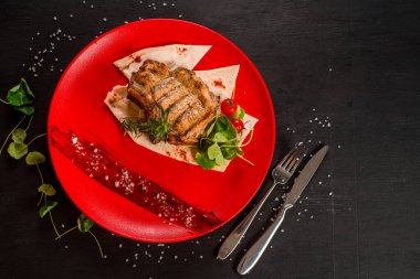 Kırmızı tabakta taze ızgara mermer biftek.