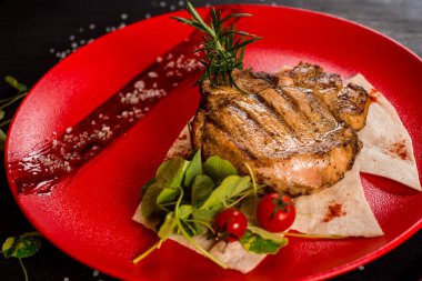 Kırmızı tabakta taze ızgara mermer biftek.