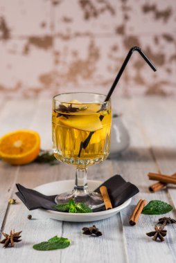 Ahşap arka planda portakallı, beyaz şaraplı bir bardak.