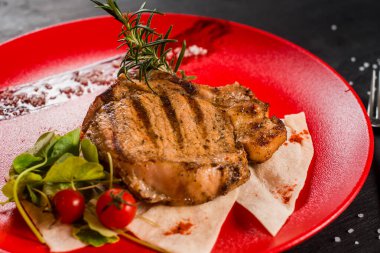 Kırmızı tabakta taze ızgara mermer biftek.