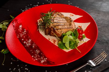 Kırmızı tabakta taze ızgara mermer biftek.