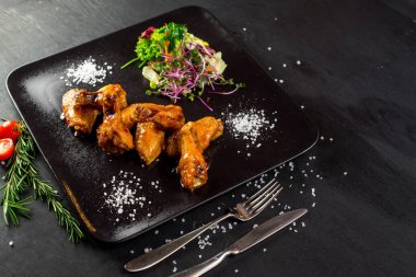 Siyah arka planda sebzeli kızarmış tavuk budu.