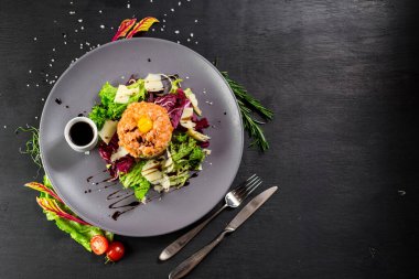 Siyah ahşap arka planda bir Tatar yemeği.