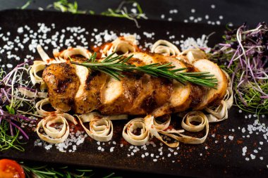 Siyah arka planda ızgara tavuk eti madalyonu.